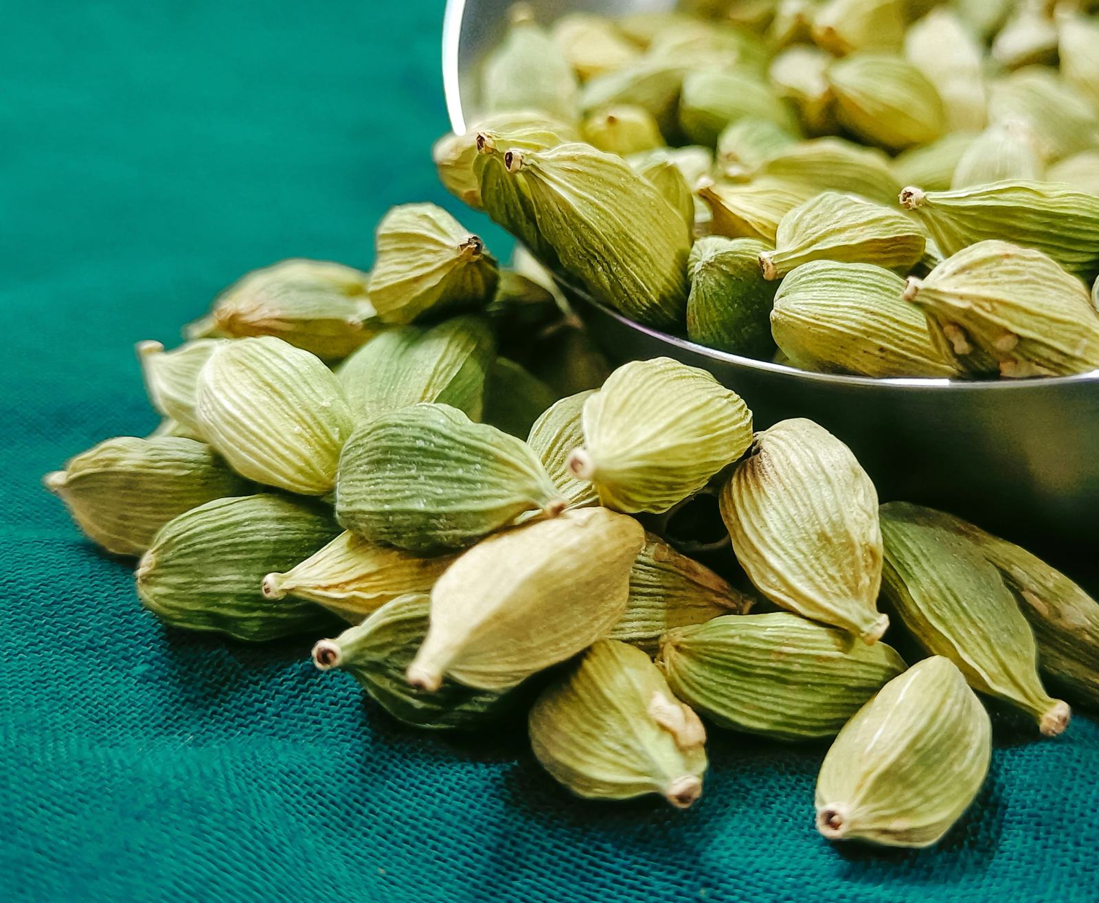 A metal bowl of green cardamom pods