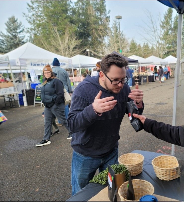 Sharing a bag of Somara coffee with a customer at a Saturday farmers market