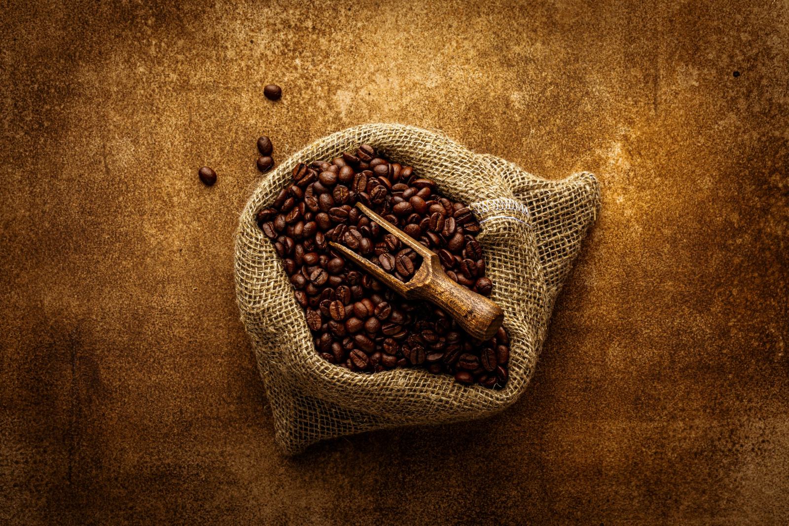 A burlap sack of roasted coffee beans with a scoop